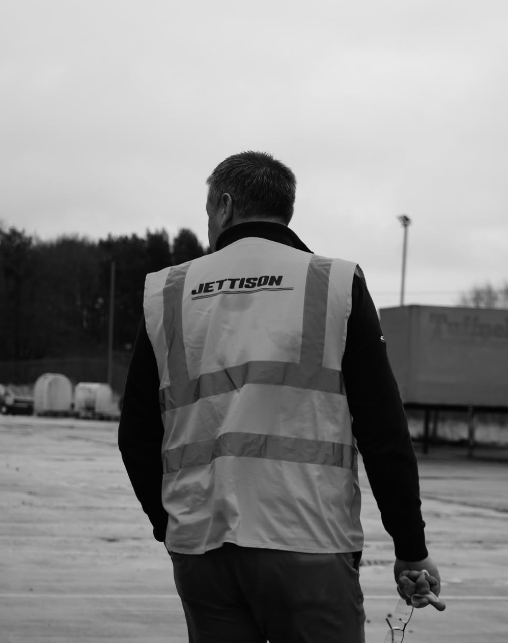 Worker in a Jettison-branded hi-vis vest walking on an industrial yard